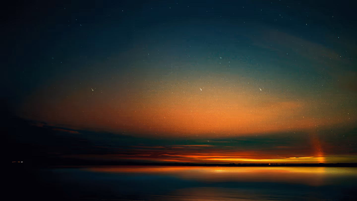 Vivid sunset over calm water with vibrant orange and blue hues, tranquil evening sky.