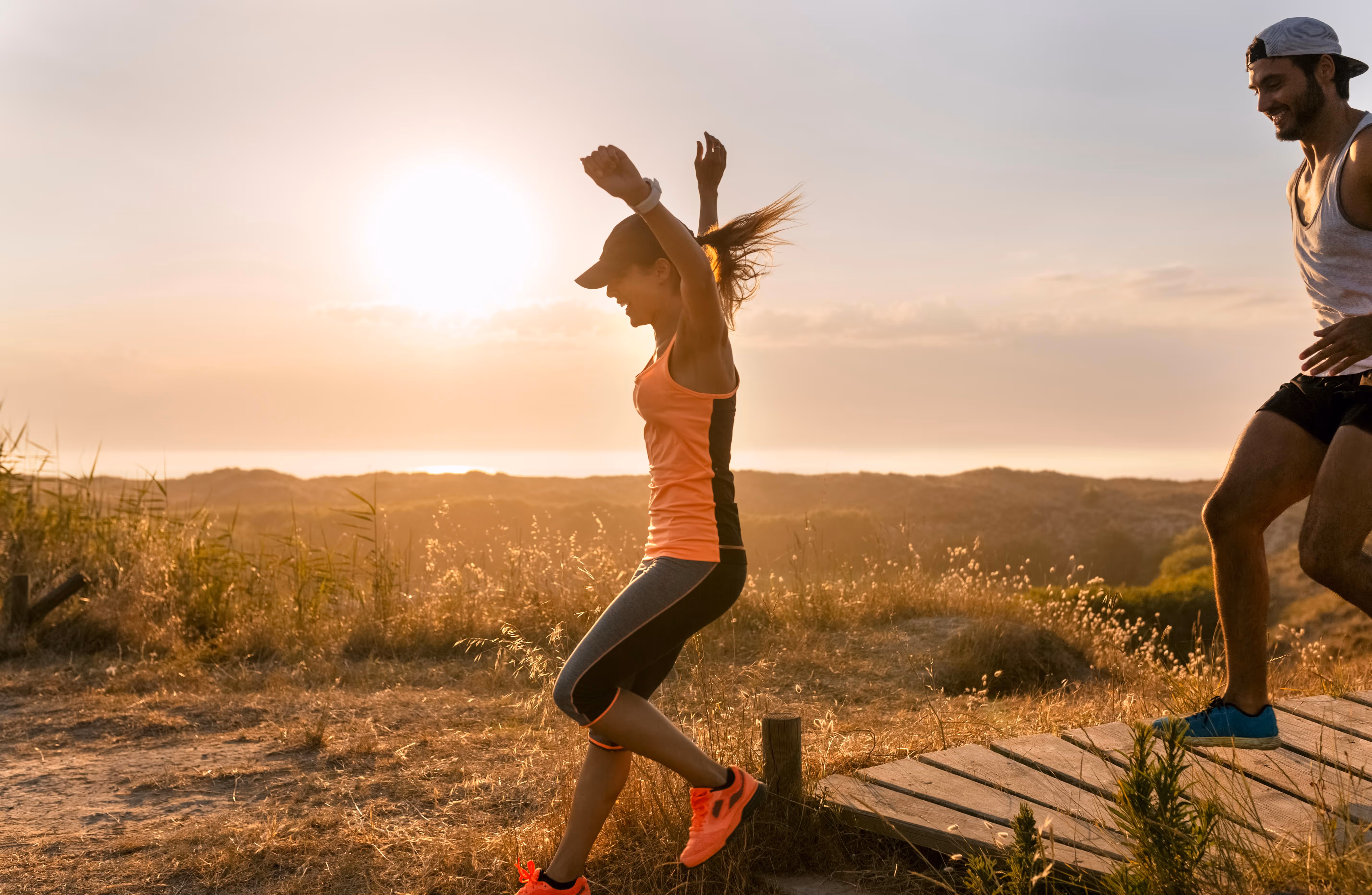Happy fit couple running outside  enjoying the beauty of life through a primal movement . 