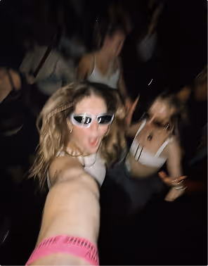 A blurry selfie of two women dancing to music in a dark club. 