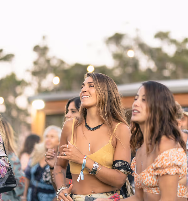 two woman dressed in summer festival attire smile as they trip they planned on Pilot has made their trip a success. 