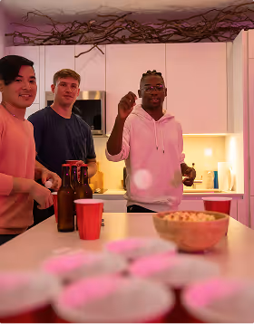 a black man throws a ping pong ball for a beer pong shot