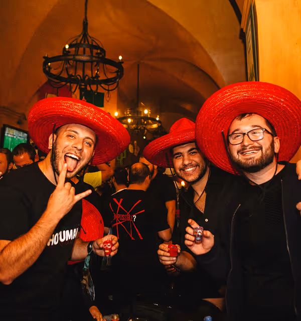 three men in red sombreros celebrate during a bachelor party planned on Pilot. 