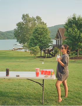 A woman stands by a beer pong table waiting to shoot at a Bachelorette Party planned on Pilot. 