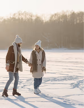A couple holds hands and skates across a snowy pond on an anniversary trip planned on Pilot. 