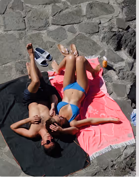 A man in a black swim suit and woman in blue bikini sunbathe on a romantic weekend planned on Pilot. 