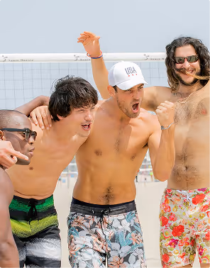 Four men celebrate a volleyball victory in swim trunks during a mates trip planned on Pilot. 