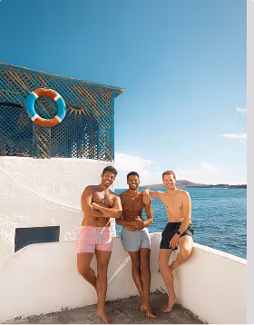 Three men pose shirtless in swim trucks during a guys trip planned on Pilot. 