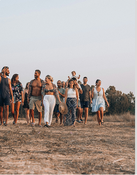 Group of people walking together outdoors on dry ground with trees in the background during daylight, during a family trip planned on Pilot.