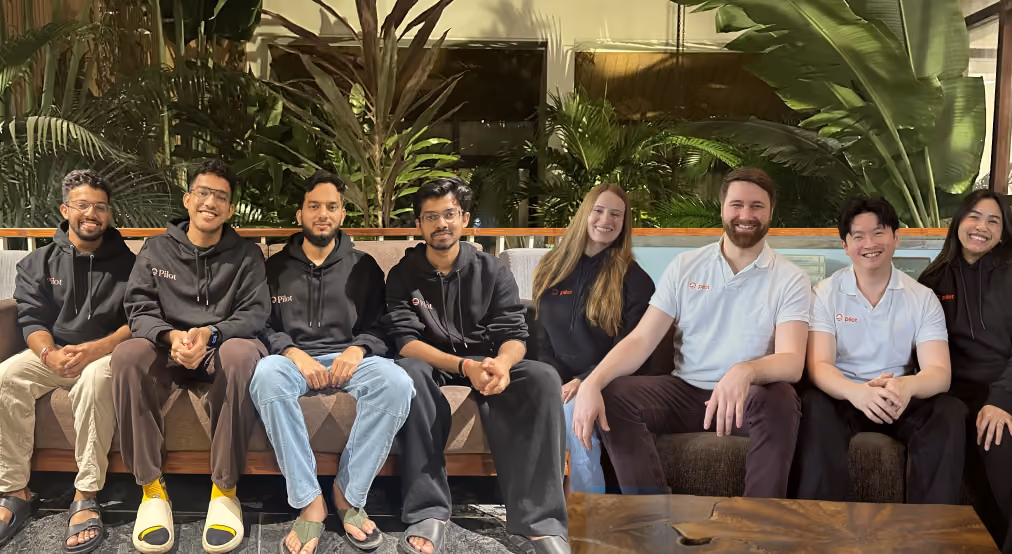 The Pilot team sitting together on a couch in matching Pilot gear