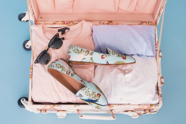 Organized suitcases with folded clothes shoes and sunglasses