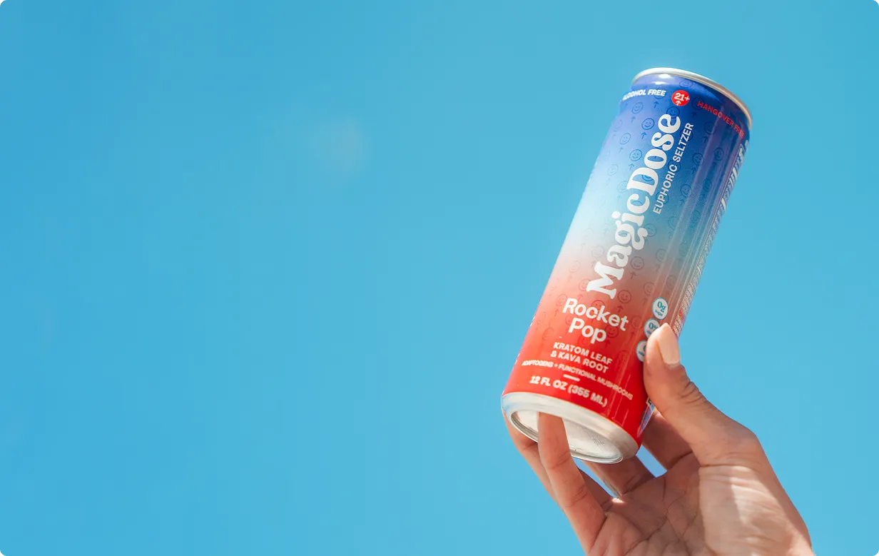 Hand holding a Magic Dose Rocket Pop can against a blue sky