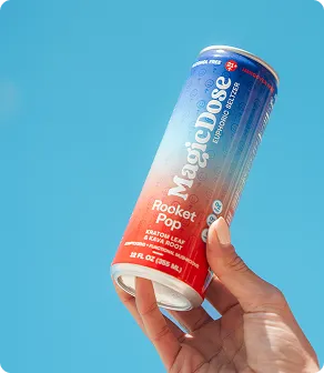 Hand holding a Magic Dose Rocket Pop can against a blue sky