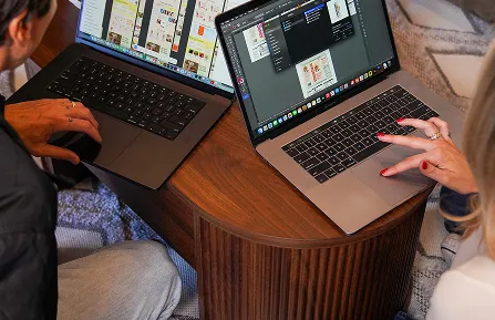 Two designers reviewing website designs on laptops