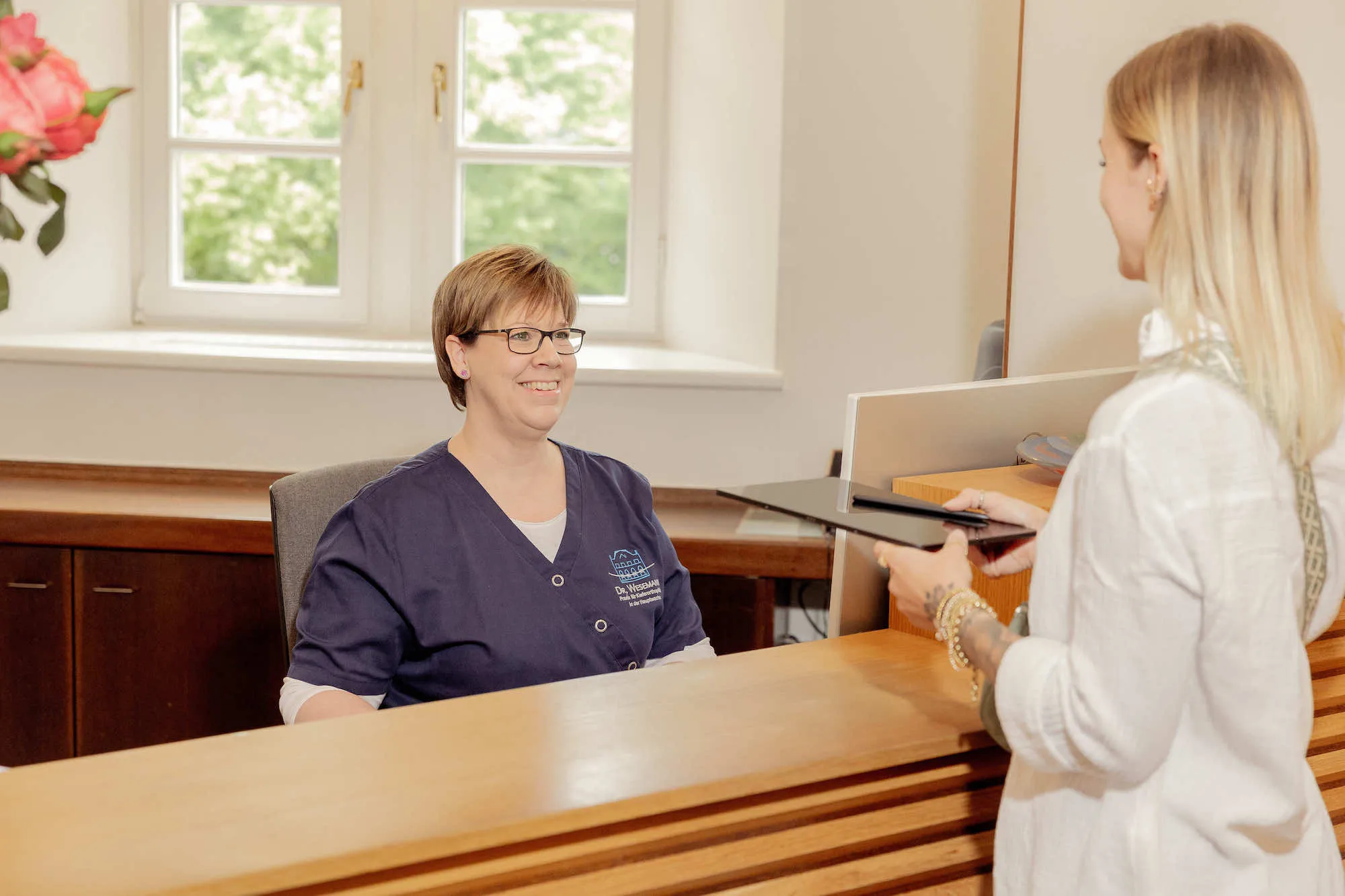 a woman sitting at a desk talking to another woman