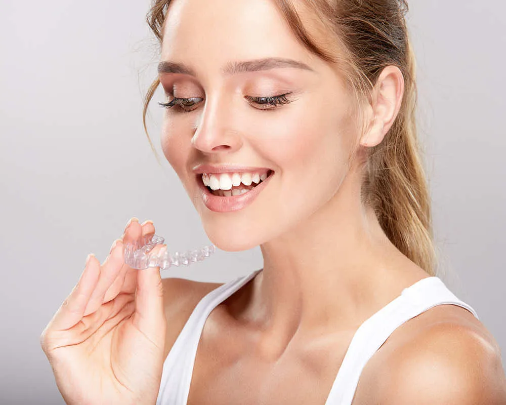 a woman smiling and holding a toothbrush in her hand