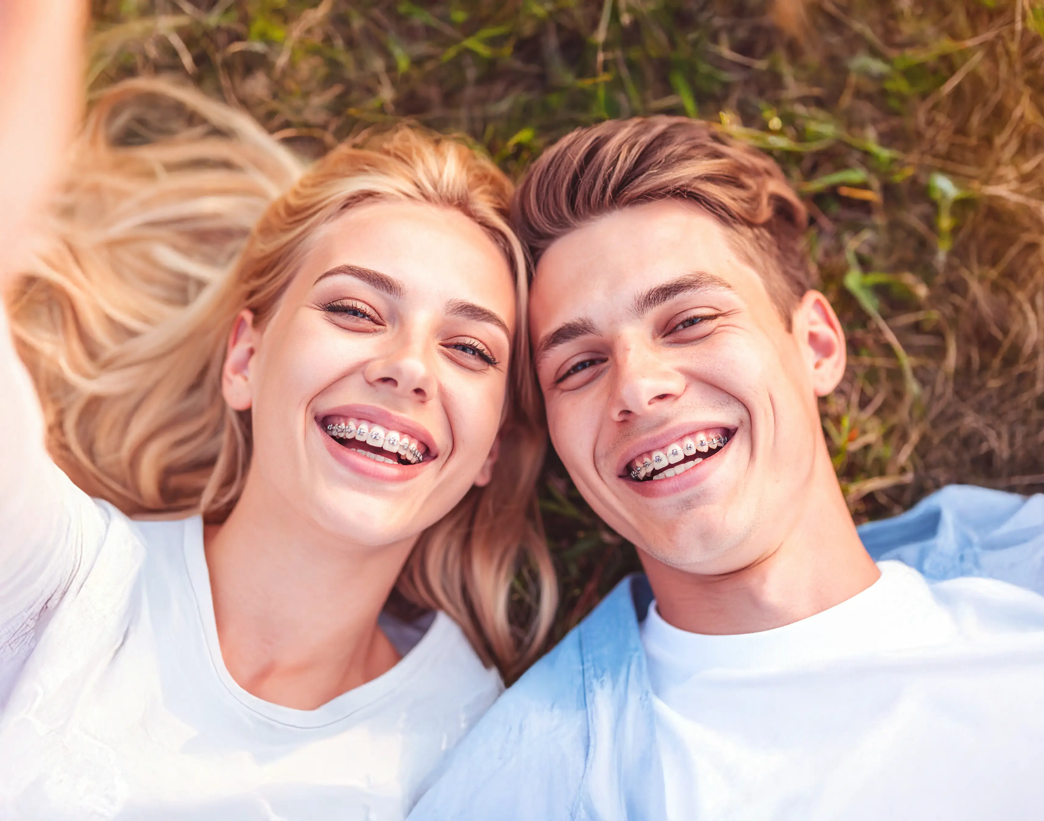 Man and woman very pretty lying in the field with braces and laughing