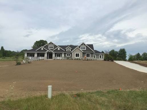 Hydroseeding in progress — green slurry spraying across bare graded soil on a Connecticut property