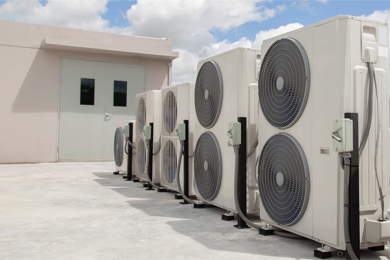 A row of air conditioning units lined up against a wall.