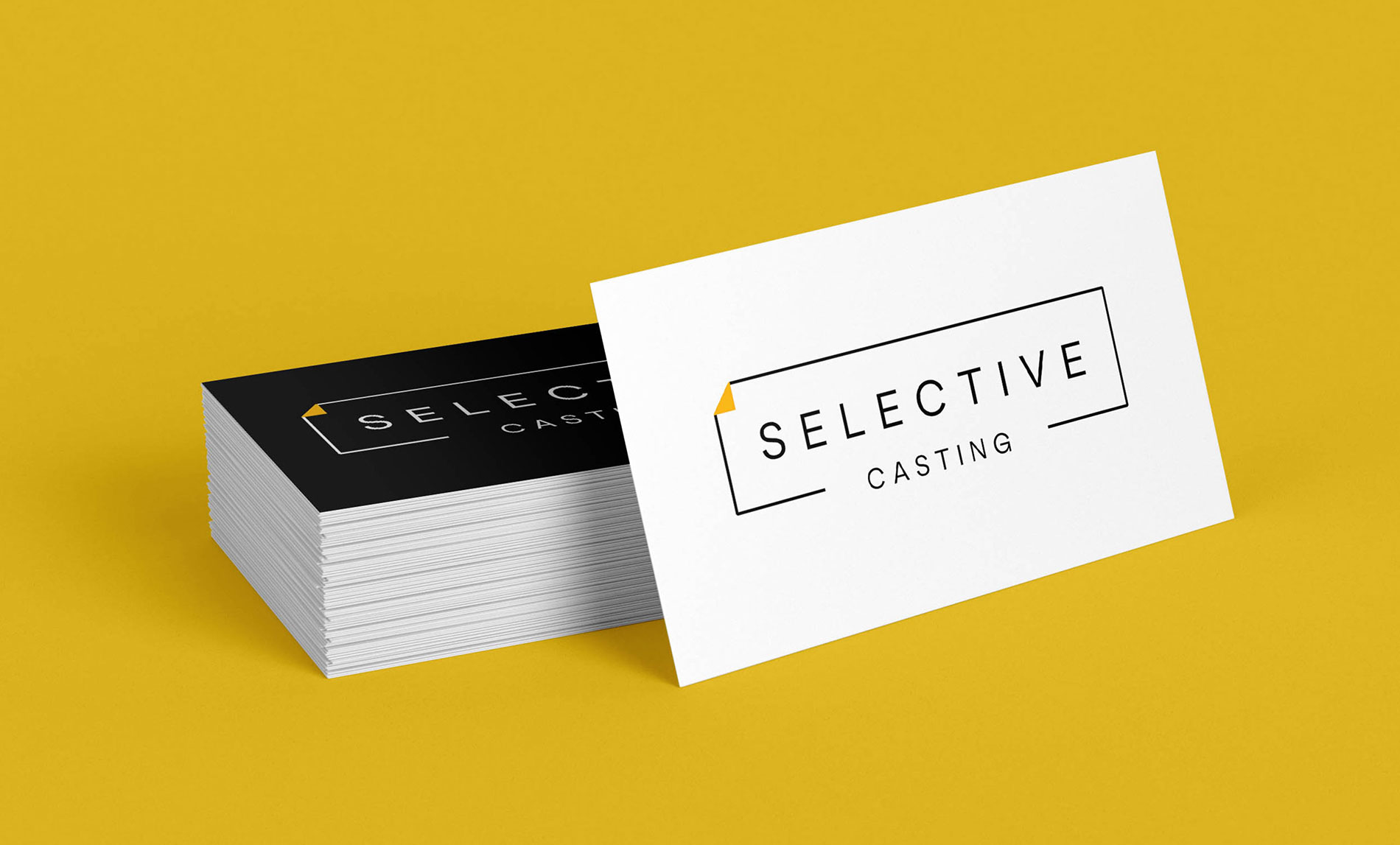 This is an image of a stack of Selective Casting business cards. The backside of the cards alternate between floods of black or white color, and the stack is against a yellow background.