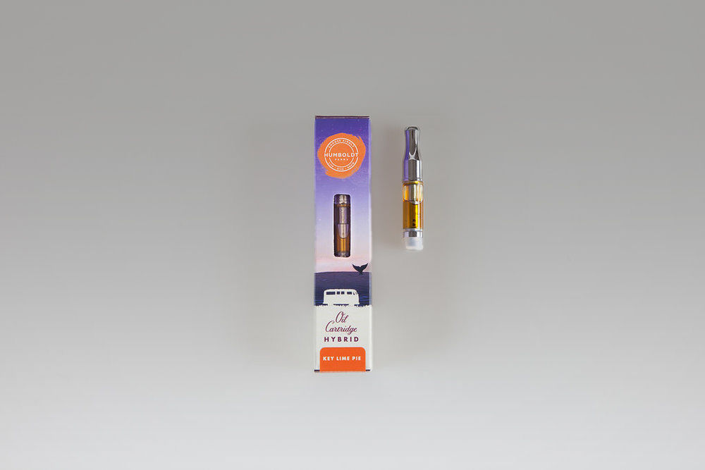 This is a photograph of the Humboldt Farms packaging for an oil cartridge. There is a purple colored box and a cartridge next to it. The variety is a Hybrid, specifically, Key Lime Pie.