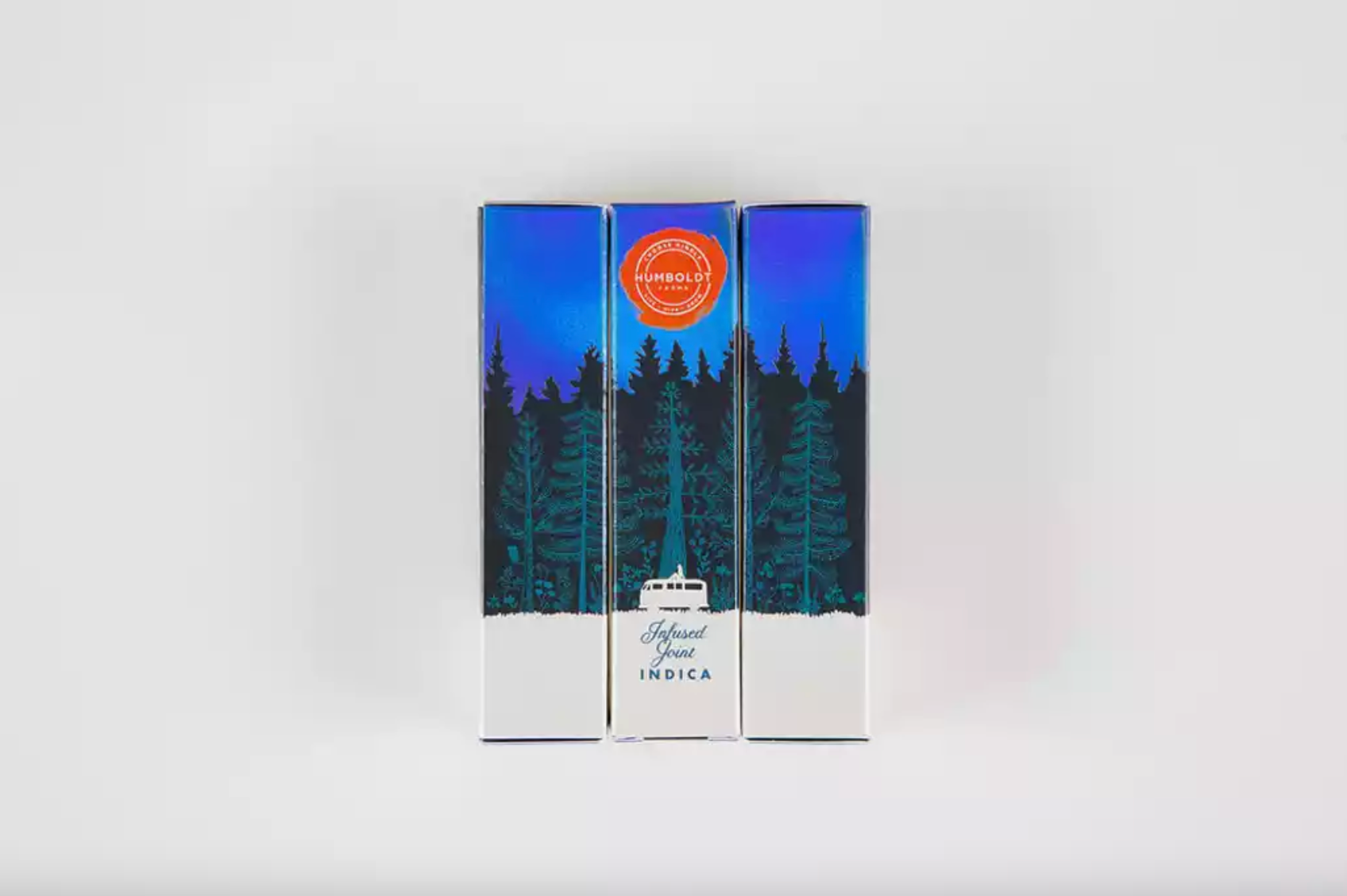 This is an image of three different sides of the same Humboldt Farms infused joint outer packaging box laid next to each other. You can tell that the illustration wraps around the entire box because there is a seamless illustration of a forest with a blue night sky across all three.