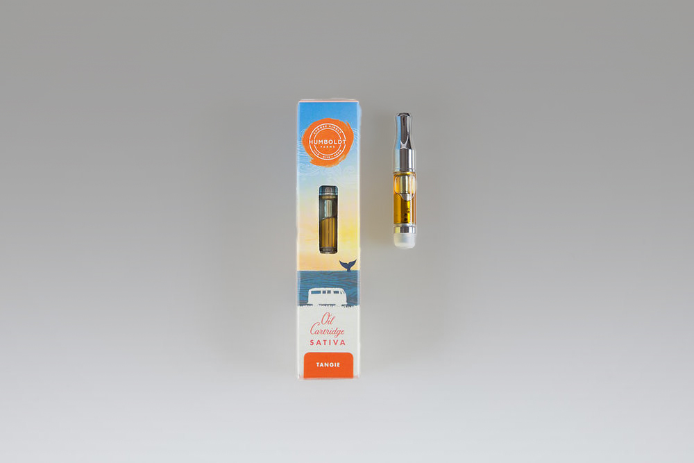 This is a photograph of the Humboldt Farms packaging for an oil cartridge. There is a yellow to blue gradient colored box and a cartridge next to it. The variety is Sativa, specifically, Tangie