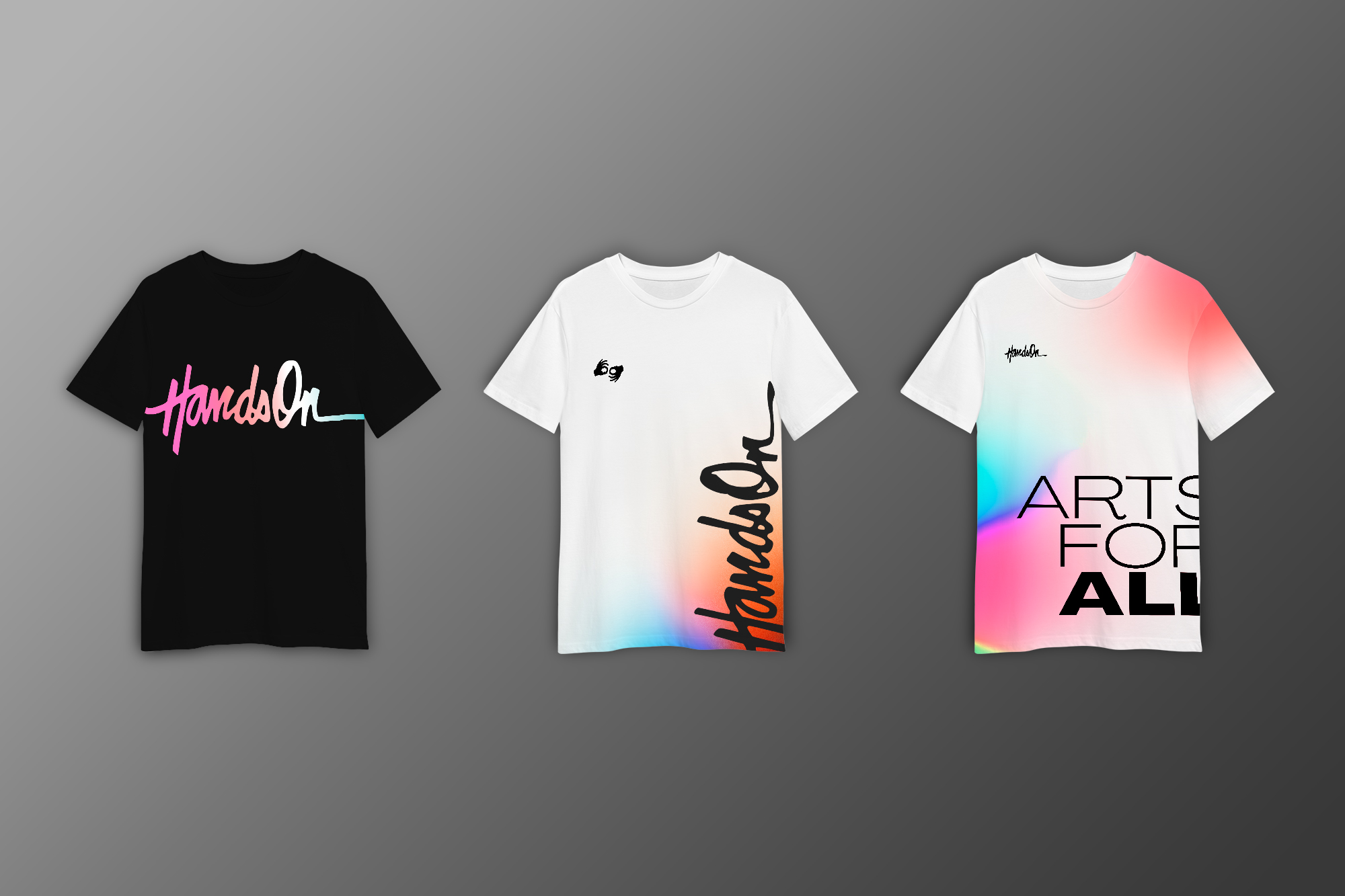 This is an image of three t shirts on a gray background that were designed for Hands On. The t shirt to the fair left is black, with the organization's logo enlarged and centered on the chest with a colorful gradient fill. The shirt in the middle is white, with a splash of color in the (same gradient) at the bottom of the shirt and the logo enlarged and vertically placed. The shirt on the far right is white but features the gradients and has large text that reads "Arts for All" wrapped around the right edge of the shirt.