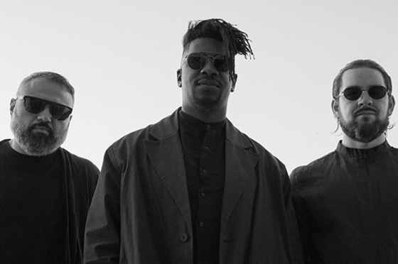 Young woman with short red hair and freckles, wearing a sleeveless striped top, lying on a bed with a leafy patterned cover.