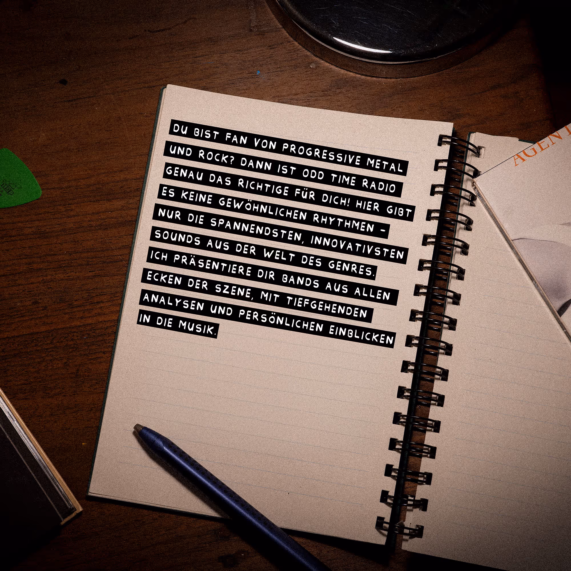 Notebook with German text describing Odd Time Radio as a source for progressive metal and rock with innovative rhythms and deep music analysis, placed on a wooden desk with a blue pen and a guitar pick.