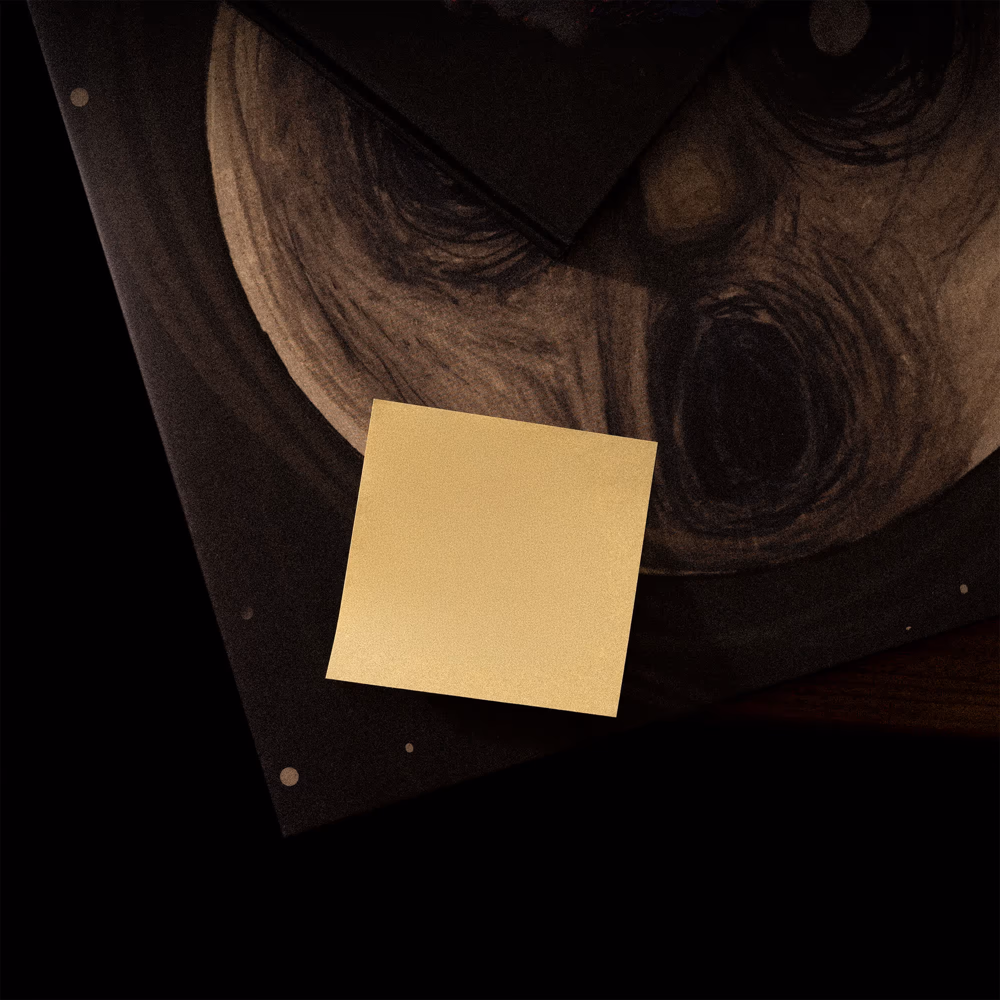 Gelber quadratischer Haftnotizzettel liegt auf einer dunklen Holzmaserung und einem Buch oder Magazin.