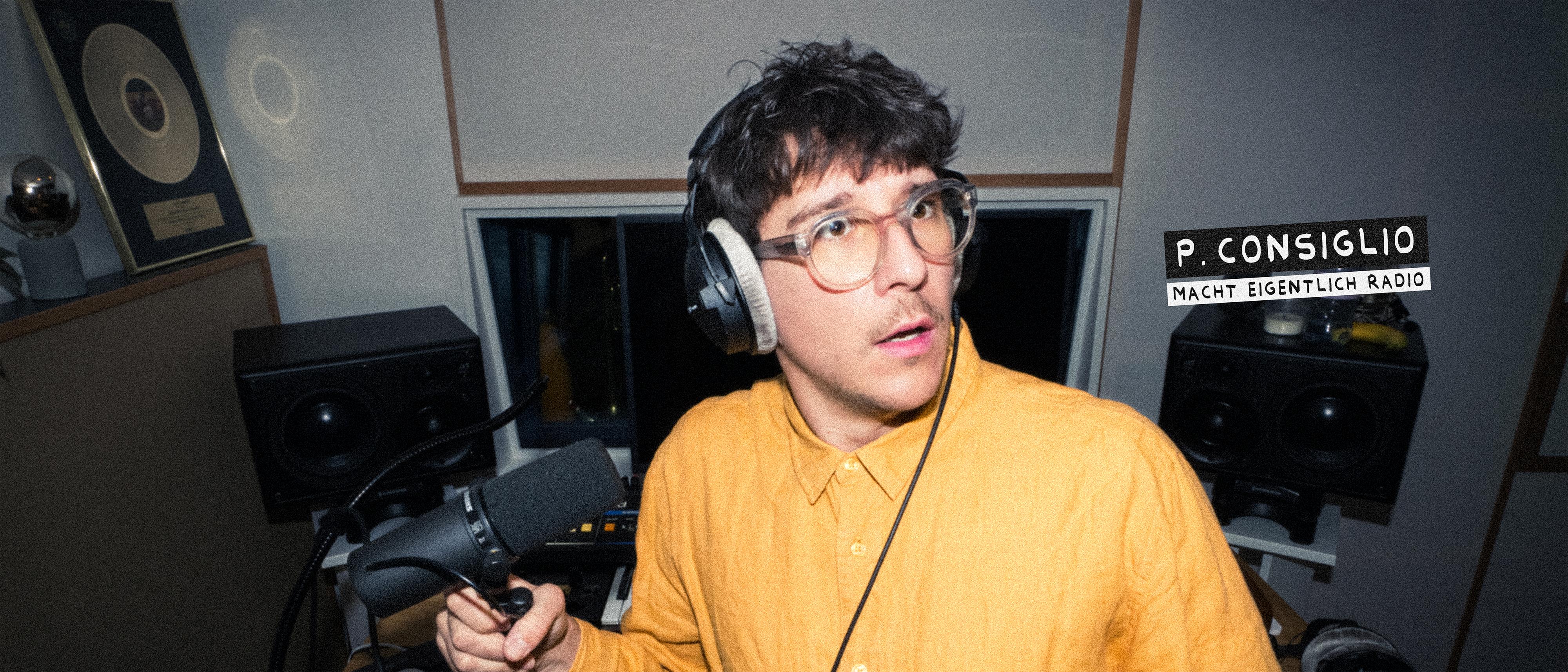Junger Mann mit Brille und Kopfhörern spricht in ein Mikrofon in einem Tonstudio.
