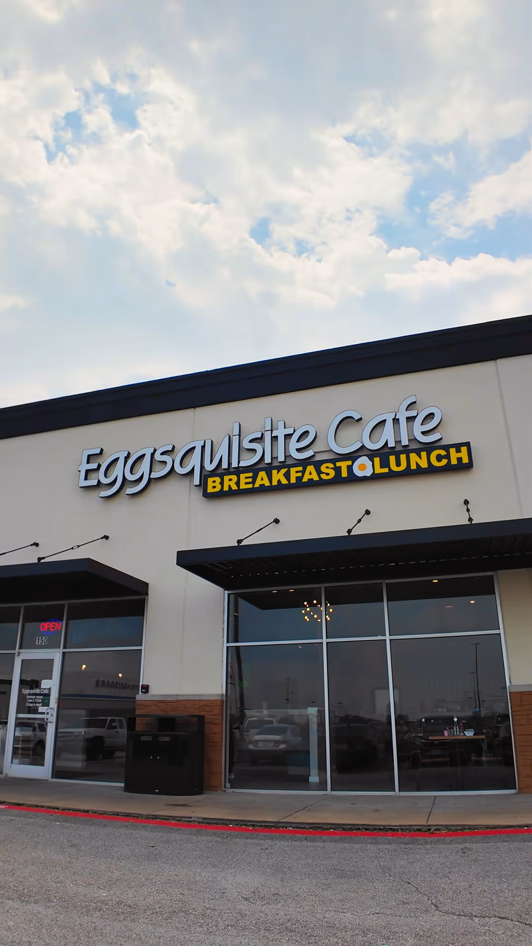 Front entrance of Eggsquisite Cafe with sign advertising breakfast and lunch.