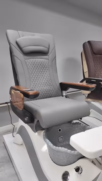 Modern gray pedicure spa chair with wooden armrests and a textured seat back.