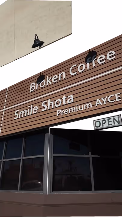 Storefront with wooden panel signage displaying 'Broken Coffee', 'Smile Shota', and 'Premium AYCE', with an open sign below.