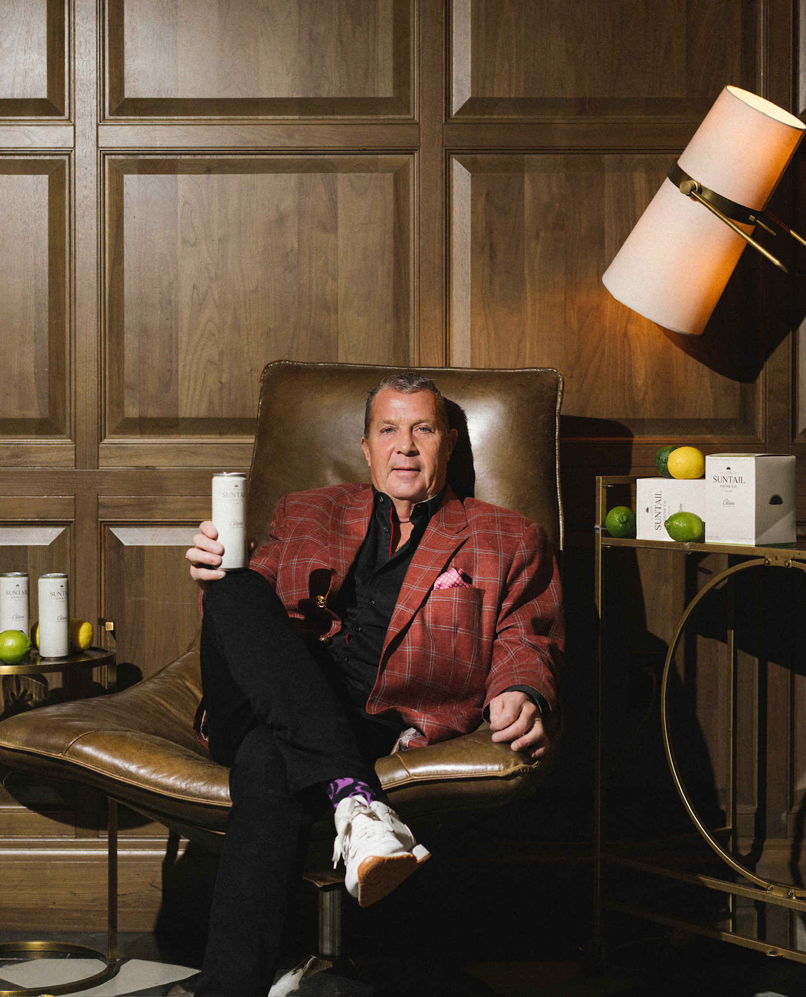 Hand holding a white Suntail Drink Co. Sandia lemon watermelon tequila cocktail can against a beige background.