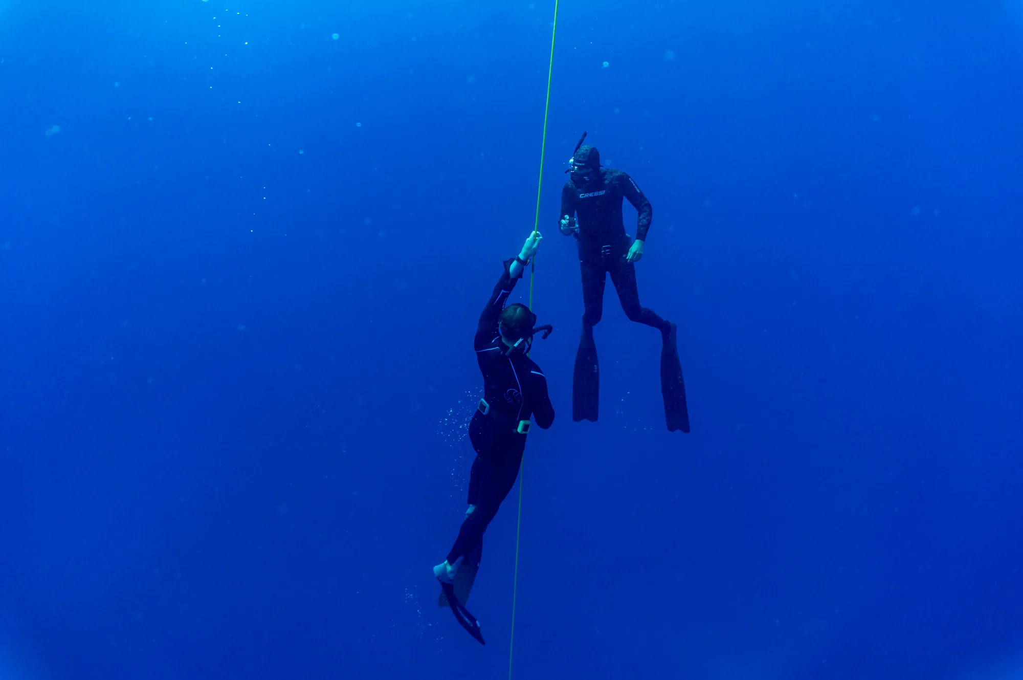 Zwei Apnoetaucher neben einem Führungsseil im blauen Meer
