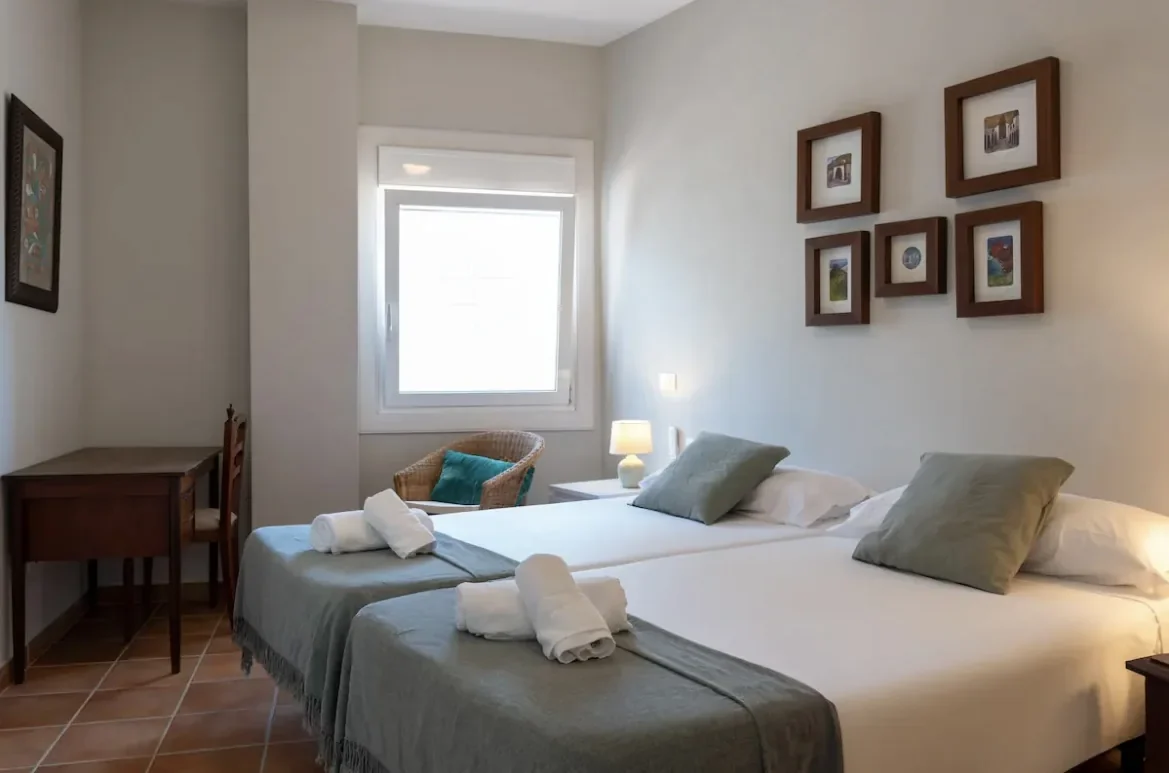 Zimmer mit zwei Betten und gerahmten Bildern an der Wand