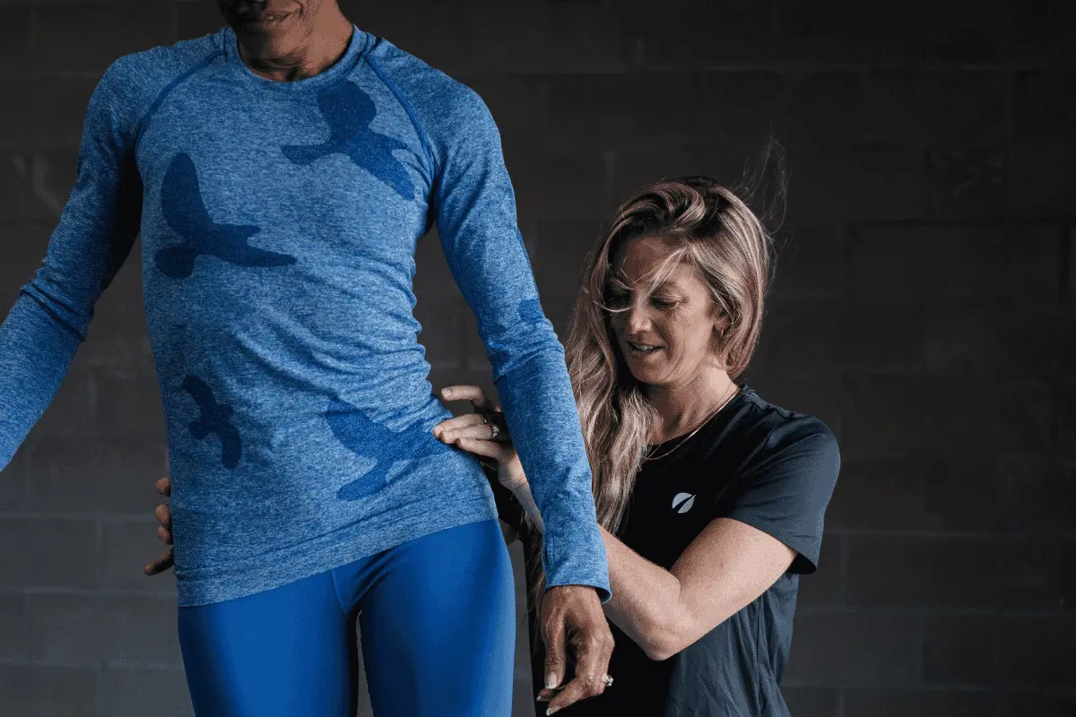 Personal trainer adjusts hips of female runner