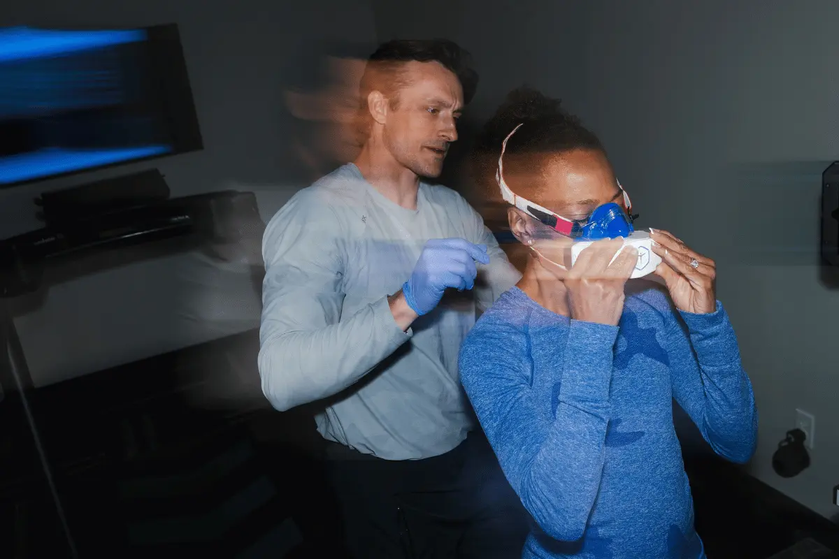 Man with gloves on straps female runner into mask for combined testing