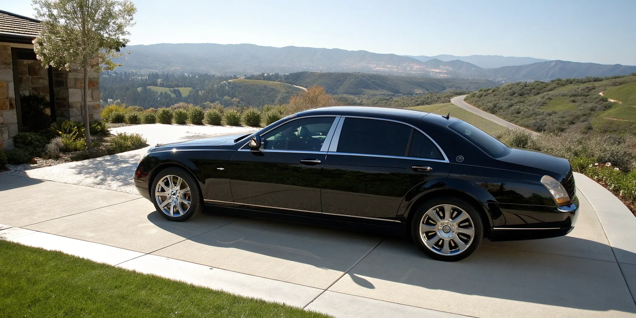 A black executive car ready for hire, parked on a scenic driveway.