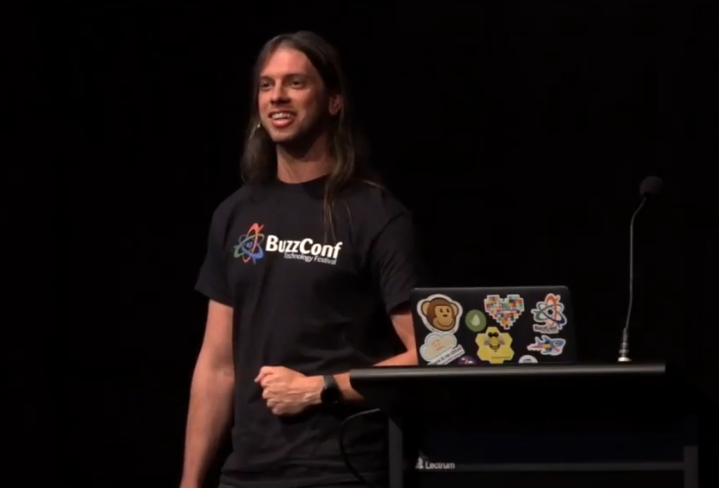 Rick Giner on stage next to a laptop, presenting on Accessibility at Decompress conference