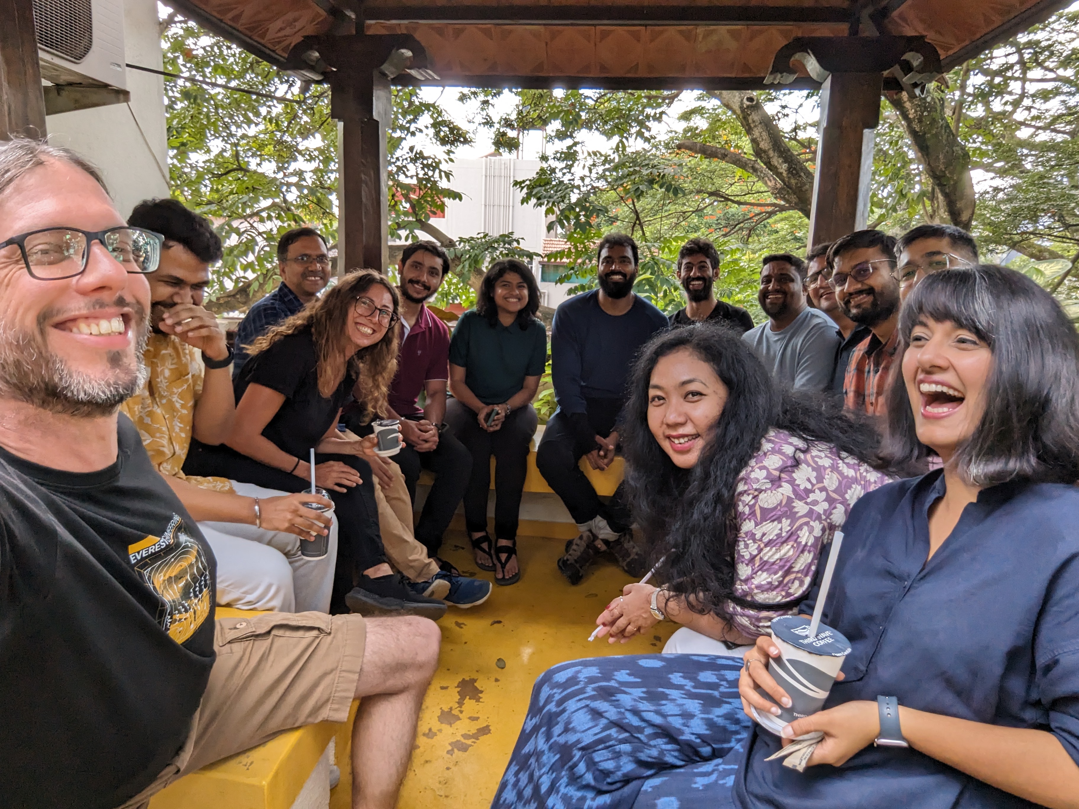 Rick Giner surrounded by a team of laughing colleagues in a pagoda in India