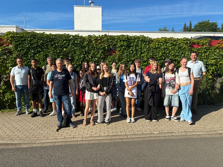 Bild vergrößern: Schülerinnen und Schüler, Lehrkräfte, Bürgermeister Christian Pospischil und Amtsleiter Frank Burghaus stehen vor einer grünen Hecke mit blauem Himmel im Hintergrund - bereit zur Buslotsenfahrt