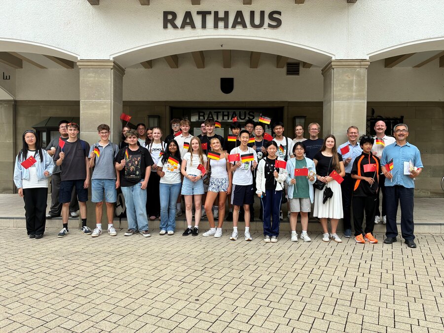 Bild vergrößern: Ddeutsch-Chinesische Jugendgruppe schwenkt deutsche und chinesische Fähnchen vor dem Attendorner Rathaus.