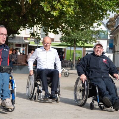 Bild vergrößern: Drei Männer im Rollstuhl.