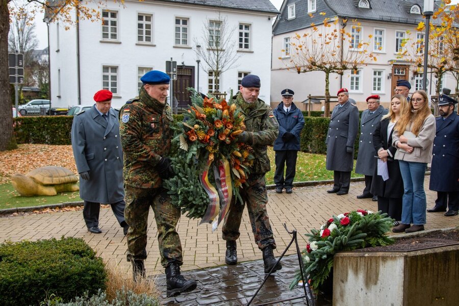 Bild vergrößern: Zwei Reservisten in Uniform die einen Kranz tragen