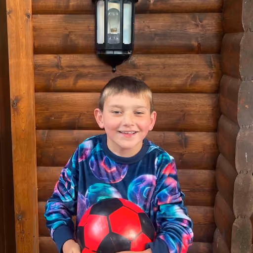 Boy in front of George Lodge holding a red football