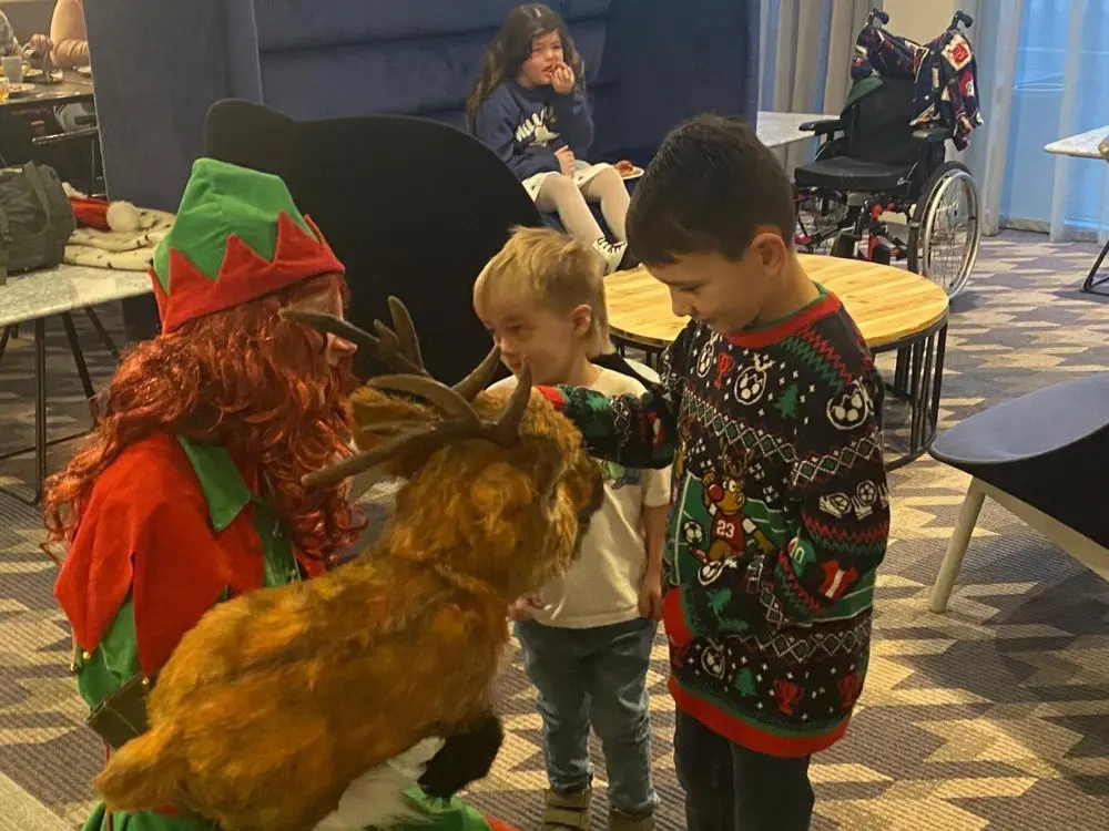 Children in Christmas jumpers gathered around to pet a reindeer puppet during the holiday sleepover.