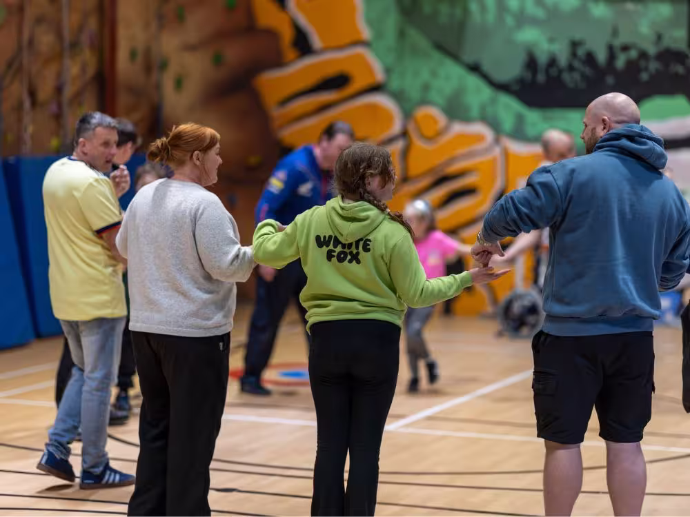 Children and adults taking part in an indoor activity session at Calvert Lakes, with a climbing wall visible in the background