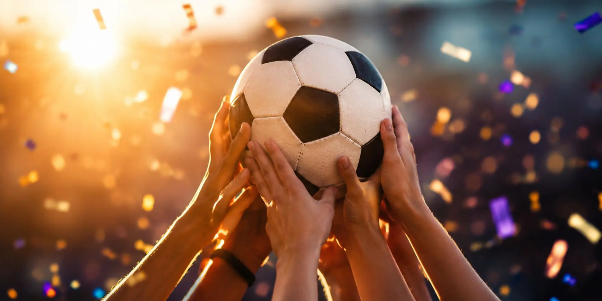 Many hands holding a football aloft